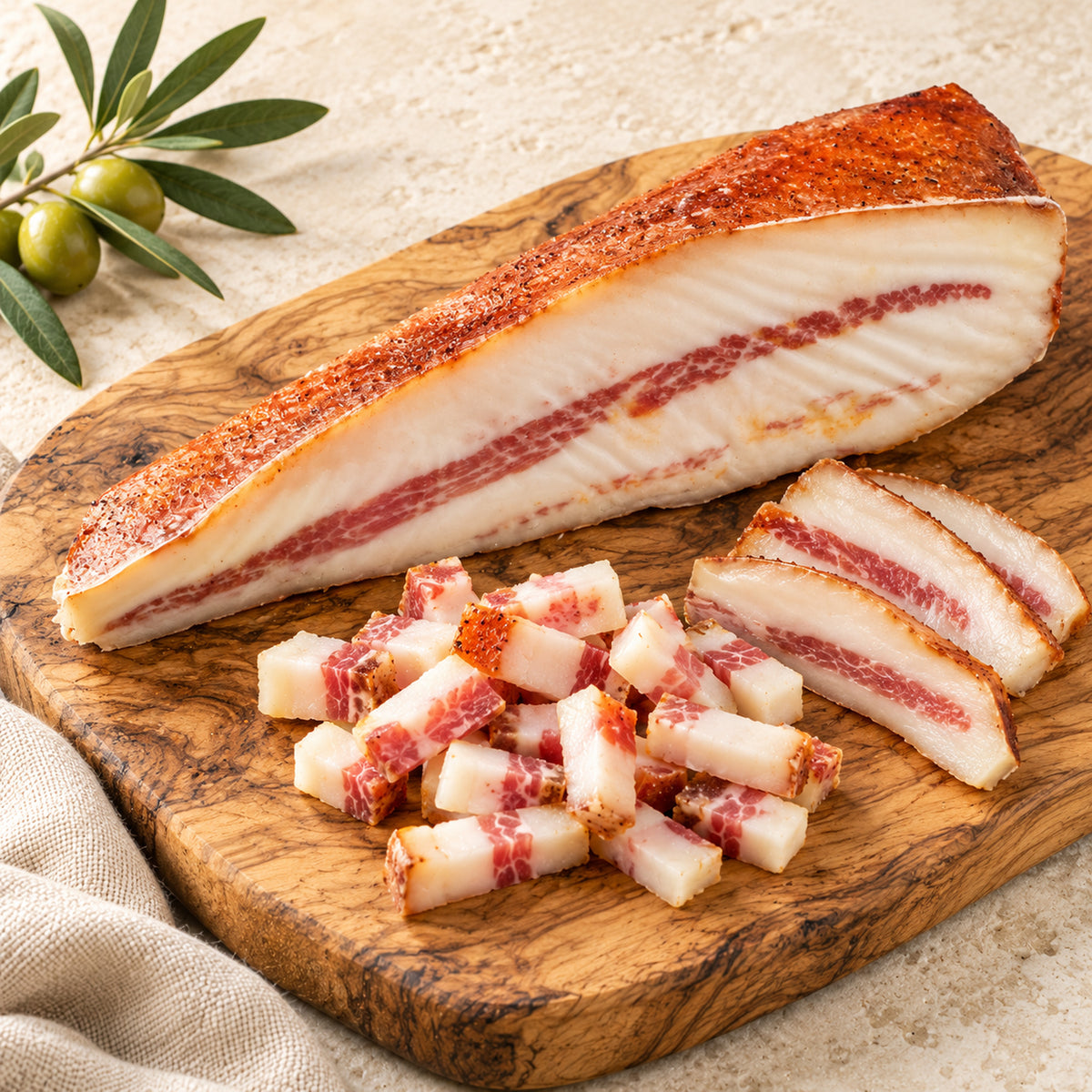 Guanciale Piccante von Bellantone auf einem Olivenholzbrett mit Scheiben und kleinen Würfeln – Serviervorschlag.