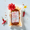 Nduja di Spilinga Bellantone vakuumverpackt auf hellem Hintergrund mit Knoblauch, schwarzem Pfeffer und Meersalz – italienische scharfe Streichsalami aus Kalabrien