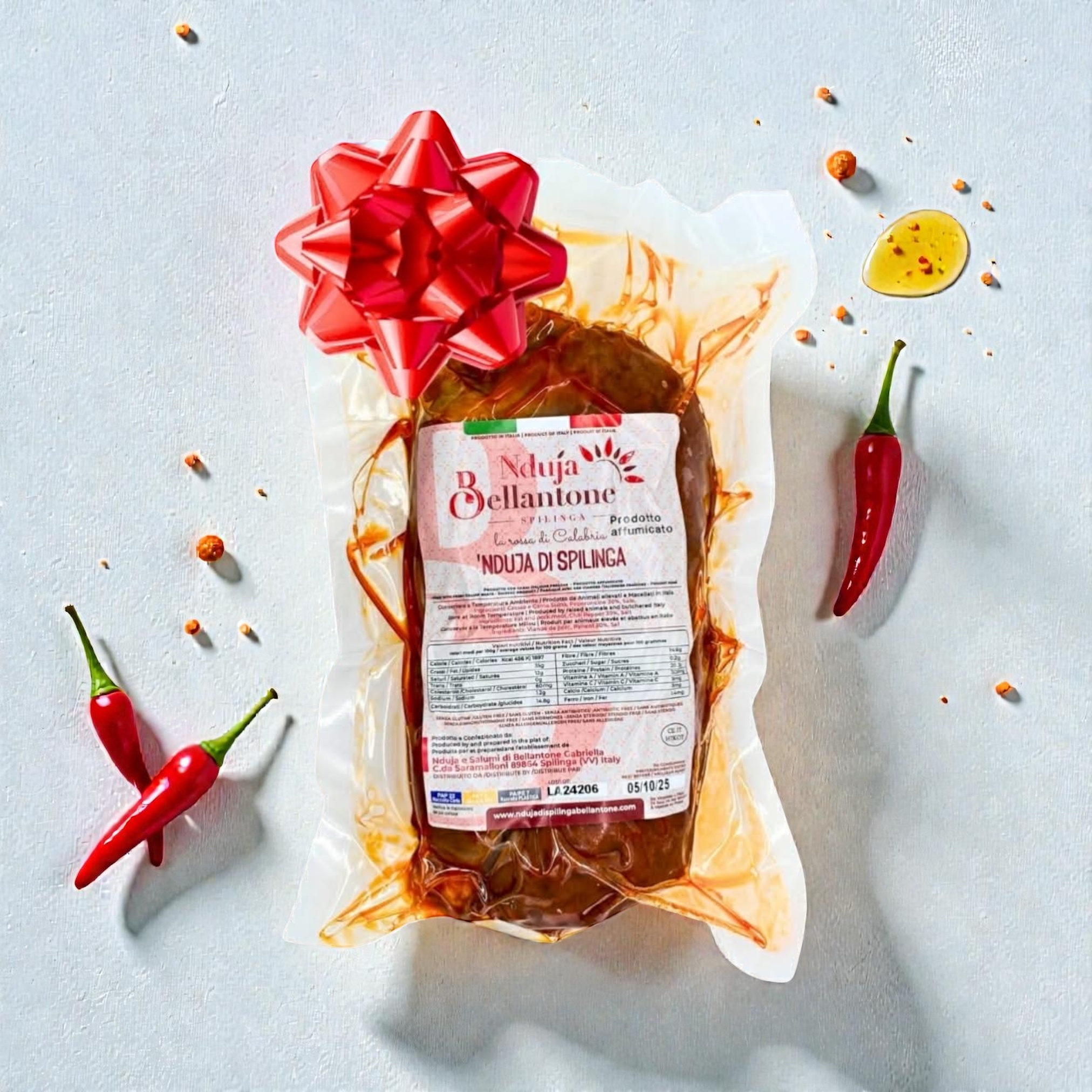 Nduja di Spilinga Bellantone vakuumverpackt auf hellem Hintergrund mit Knoblauch, schwarzem Pfeffer und Meersalz – italienische scharfe Streichsalami aus Kalabrien