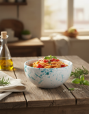 Italienische Pasta-Salat-Schüssel auf Terrasse mit mediterraner Landschaft und Olivenzweigen – italienischer Genuss Bella Italia Store