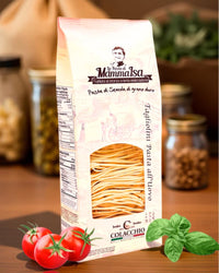 Italienische Tagliolini all’Uovo von Mamma Isa in eleganter Verpackung mit frischen Tomaten, Basilikum und Vorratsgläsern im Hintergrund