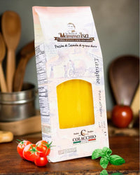 Italienische Lasagneblätter von Mamma Isa in dekorativer Verpackung mit frischen Tomaten, Basilikum und Küchenutensilien im Hintergrund