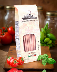 Stroncatura Pasta von Mamma Isa in rustikaler Verpackung mit frischen Tomaten, Basilikum und Vorratsgläsern im Hintergrund