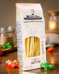 Italienische Pasta Scialatielli von Mamma Isa in rustikaler Verpackung, dekoriert mit frischen Tomaten, Basilikum und Kerze im Hintergrund