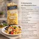 Italienische Calamarata Pasta mit Meeresfrüchten Rezept, Colacchio Pasta Verpackung neben Teller mit Garnelen, Muscheln, Oliven und Basilikum, mediterrane Küche Inspiration