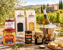 Italienisches Gourmet Paket mit Pasta, Thunfisch und Weißwein auf rustikalem Tisch in mediterraner Landschaft