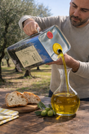 Kaltgepresstes Olivenöl aus Italien wird frisch in Glas Karaffe gegossen authentische Herstellung Apulien Premium Olivenöl