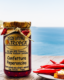 Confettura Peperoncino aus Kalabrien – scharfe Chili-Marmelade im Glas mit frischen Peperoncini und Meeresblick, serviert auf einem rustikalen Holztisch im mediterranen Stil