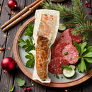 Milde kalabrische Schweinesalami aus Italien auf Antipasti-Platte, weihnachtlich angerichtet mit Tannenzweigen, Kräutern und Salamischeiben