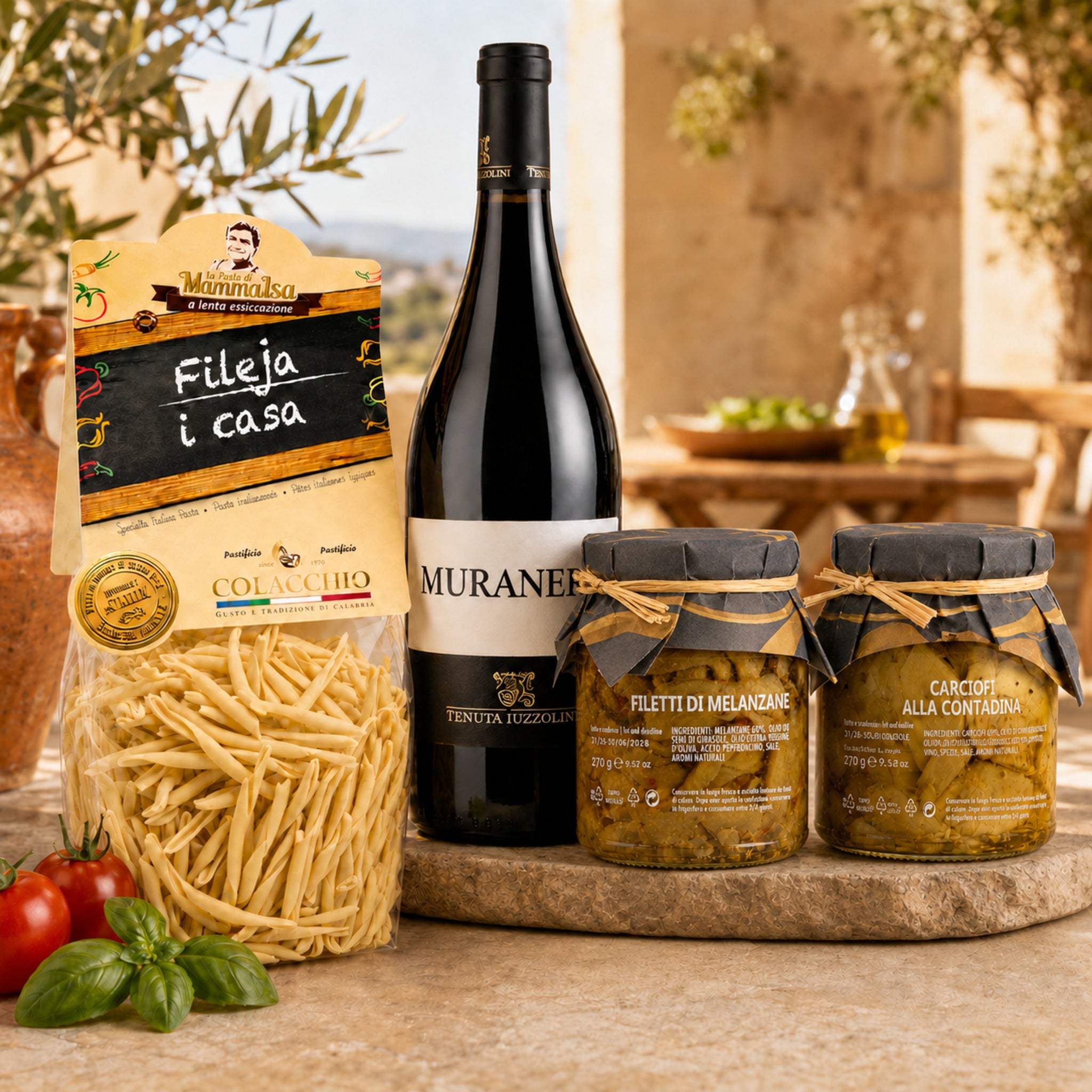 Italienisches Genuss Paket Calabria mit Pasta, Rotwein und Antipasti auf einer sonnigen mediterranen Terrasse